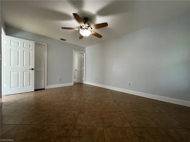 Unfurnished bedroom featuring ceiling fan and dark tile patterned floors