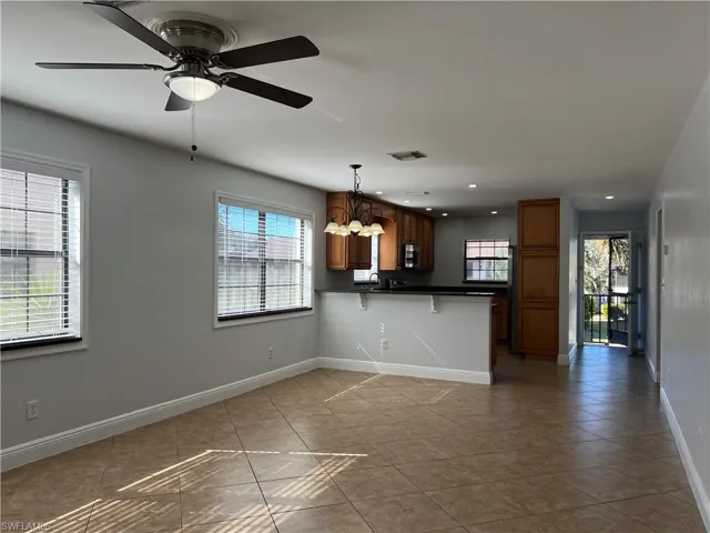 Kitchen with dark countertops, a breakfast bar area, a peninsula, wood finish cabinets, and light tile patterned flooring