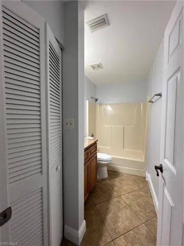Bathroom featuring vanity, a closet, shower / bathtub combination, and dark tile patterned floors