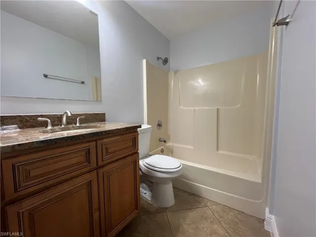 Full bath featuring vanity, bathtub / shower combination, and light tile patterned flooring