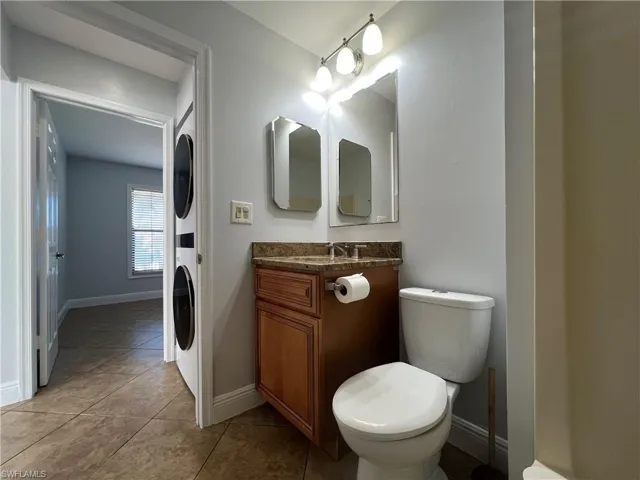 bathroom with vanity, stacked washer and dryer, and light tile patterned flooring