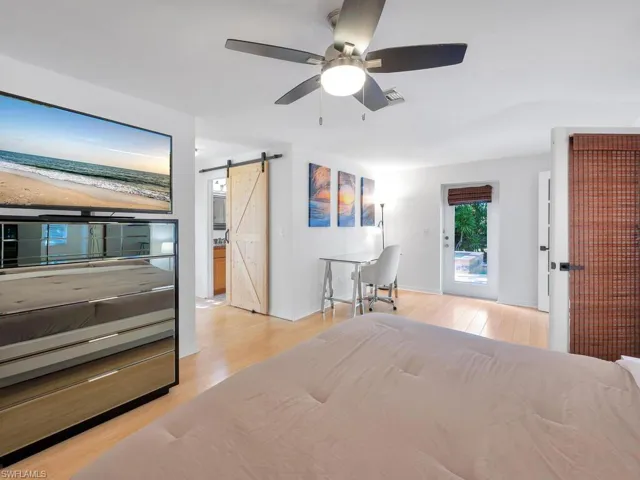 Bedroom with a barn door, ceiling fan, and light wood-type flooring