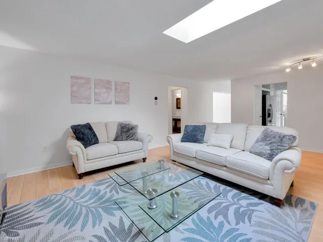 Living room with a skylight and light hardwood / wood-style flooring