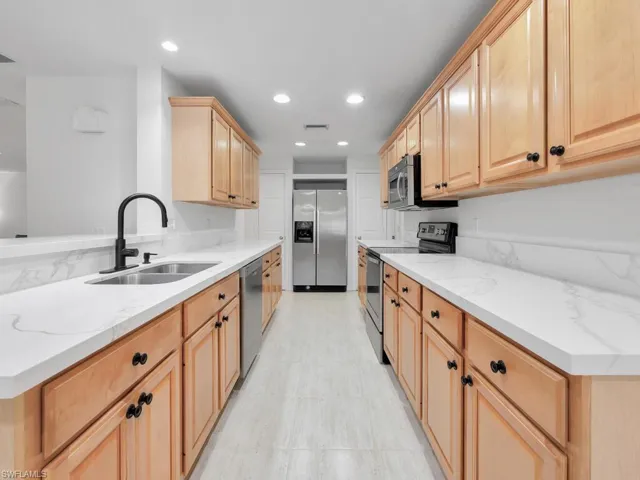 Kitchen featuring stainless steel appliances, brand new quartz countertops, sink, and custom cabinetry