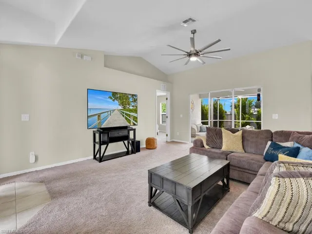 Carpeted living area featuring lofted ceiling and ceiling fan