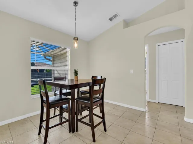 Dining space featuring light tile patterned flooring, arched walkways, and vaulted ceiling
