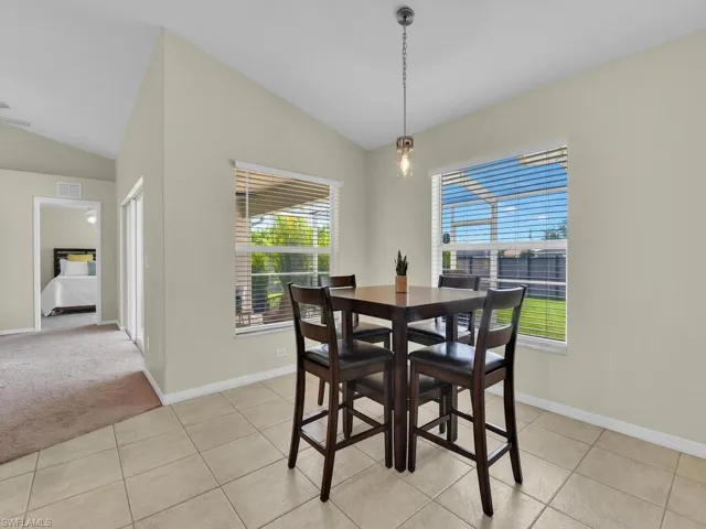 Dining room featuring lofted ceiling, light tile patterned flooring, and light colored carpet