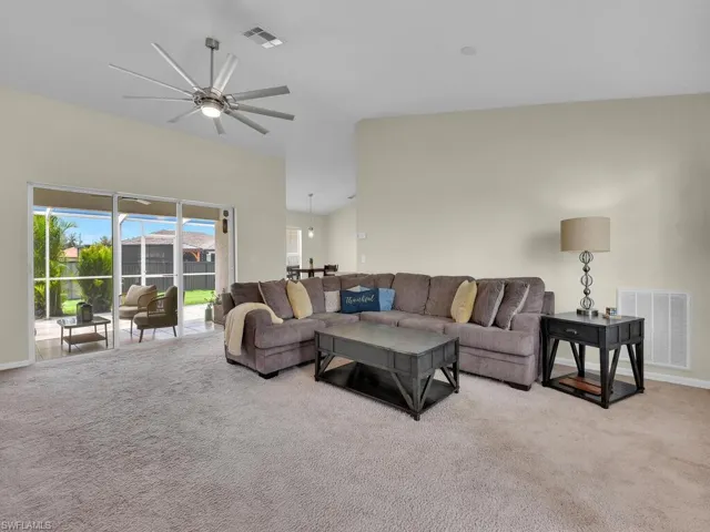 Living room featuring carpet flooring, ceiling fan, and high vaulted ceiling