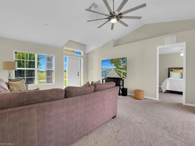 Living area featuring light colored carpet and vaulted ceiling