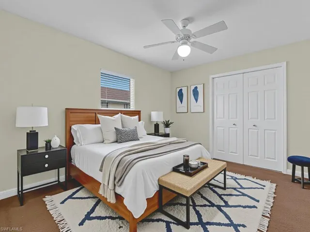 Bedroom with a closet, ceiling fan, and dark carpet