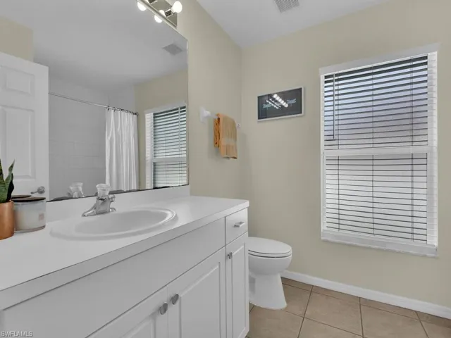 Full bath featuring vanity, light tile patterned floors, and a shower with curtain