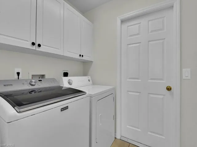 Laundry area with cabinet space, independent washer and dryer, and light tile patterned flooring