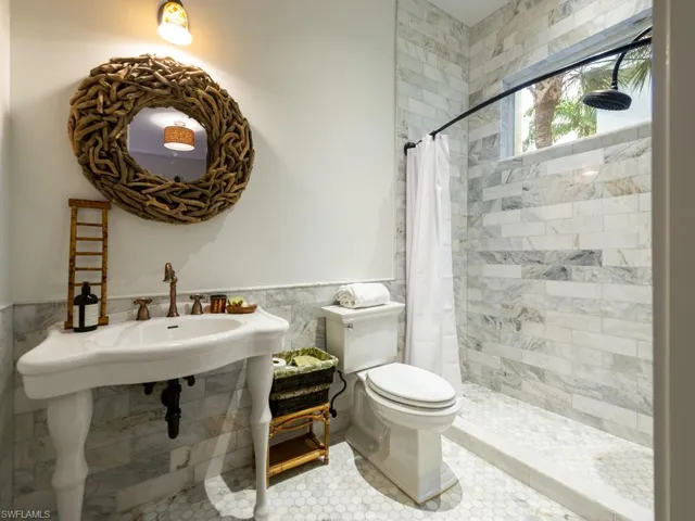 Full bathroom with tile walls, wainscoting, and tiled shower