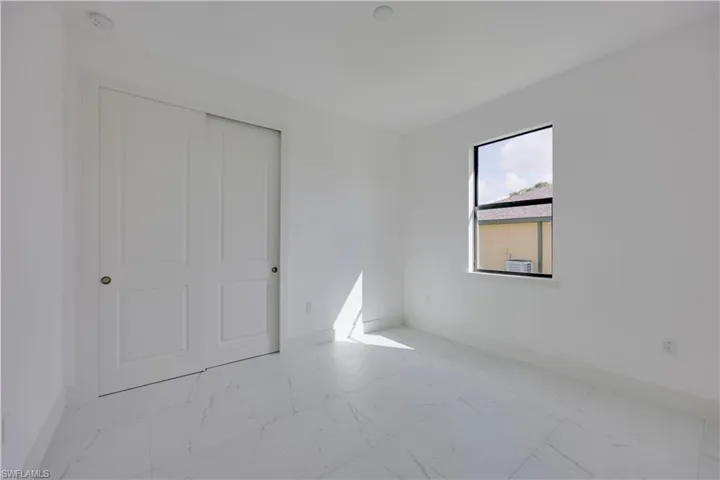 Unfurnished bedroom with light marble finish floors and a closet