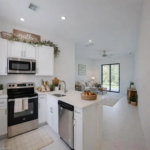 Kitchen with stainless steel appliances, a peninsula, white cabinets, open floor plan, and recessed lighting