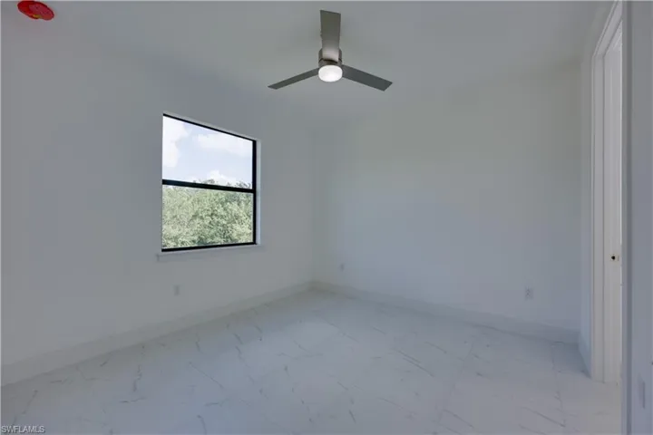 Unfurnished room featuring light marble finish flooring and a ceiling fan