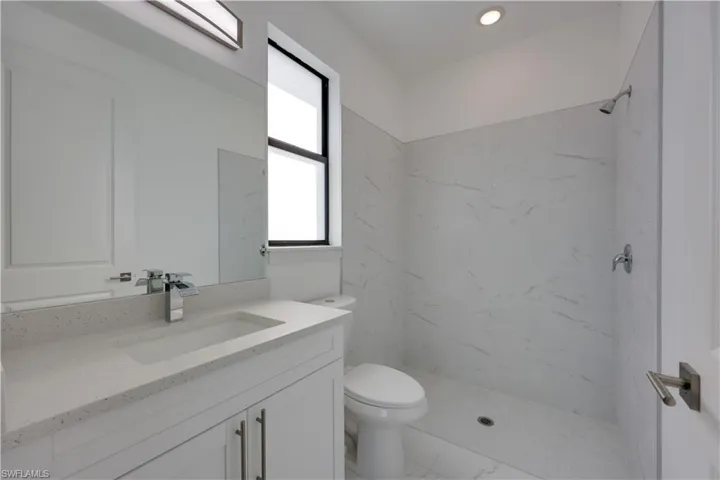 Bathroom featuring vanity, a marble finish shower, and recessed lighting