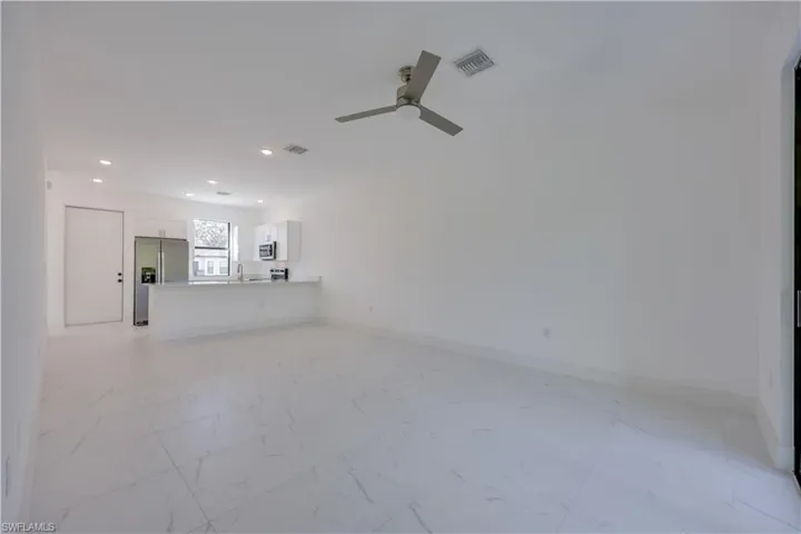 Unfurnished living room with light marble finish flooring, a ceiling fan, and recessed lighting