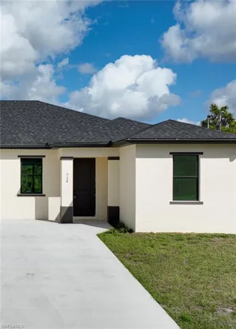 View of front of house featuring a front yard, stucco siding, and roof with shingles