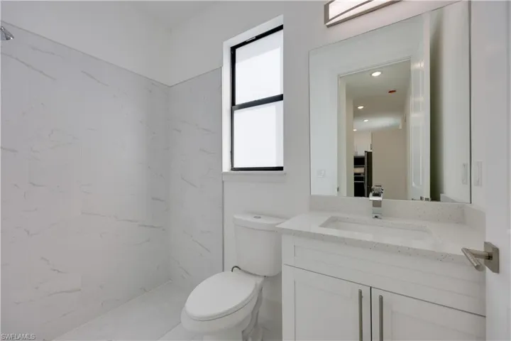 Bathroom featuring a marble finish shower and vanity