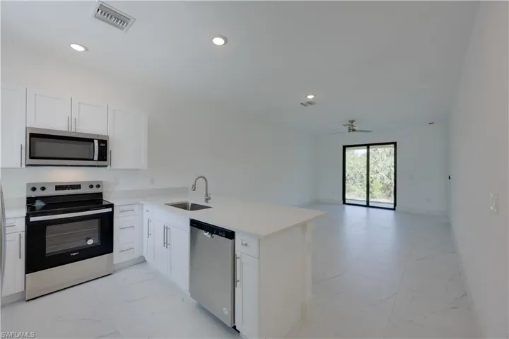 Kitchen with stainless steel appliances, light marble finish flooring, white cabinetry, and recessed lighting