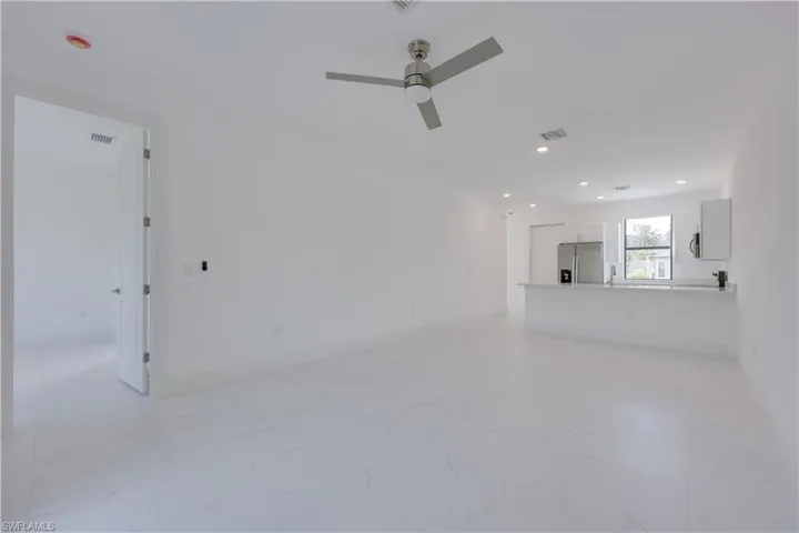 Unfurnished living room featuring ceiling fan, recessed lighting, and light marble finish floors