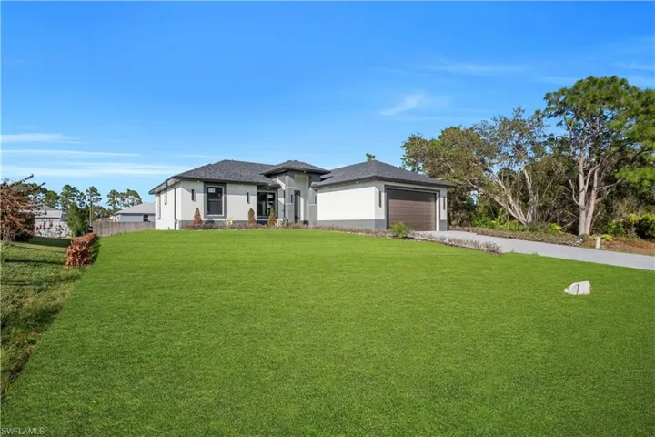 Prairie-style home featuring a front lawn, stucco siding, concrete driveway, and a garage