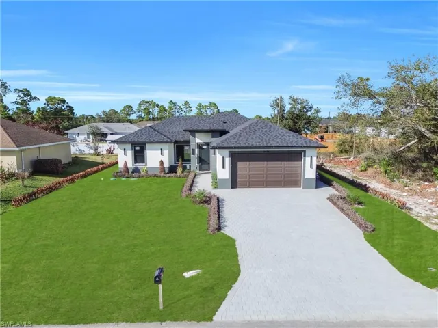 Prairie-style home featuring stucco siding, decorative driveway, an attached garage, a front yard, and roof with shingles