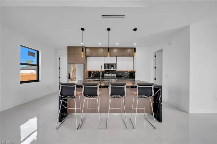 Kitchen featuring modern cabinets, a large island, pendant lighting, stainless steel appliances, and decorative backsplash