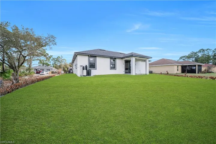 Back of house with a lawn and stucco siding