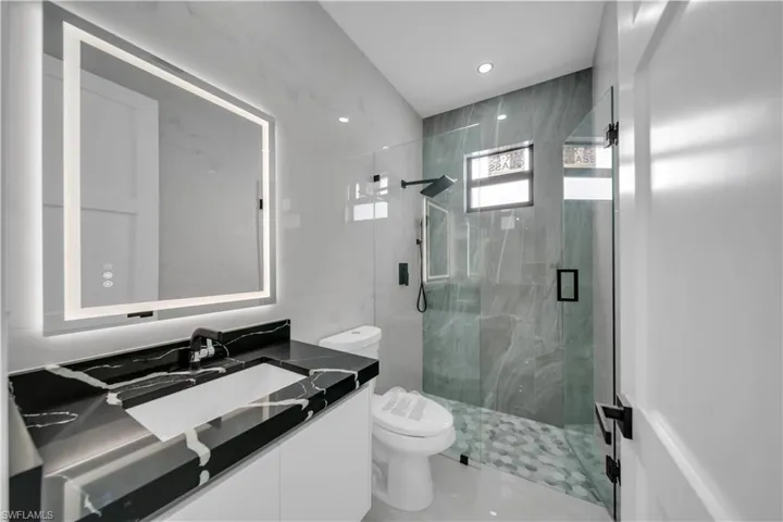 Full bathroom featuring vanity, a marble finish shower, and recessed lighting