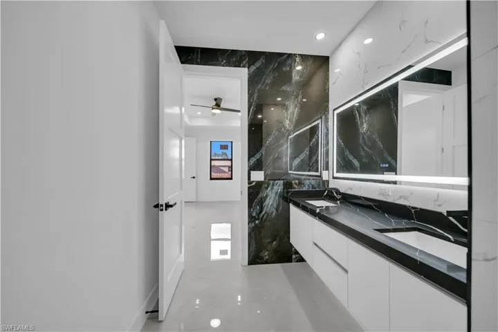 Bathroom featuring double vanity, recessed lighting, stone wall, and a ceiling fan