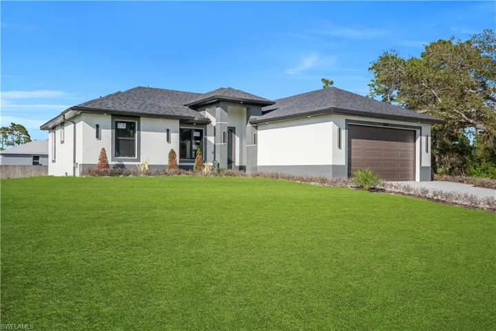 Prairie-style house with a front lawn, a garage, stucco siding, driveway, and a shingled roof