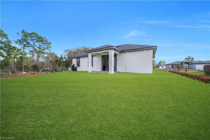 Back of property with stucco siding, a lawn, and a patio area
