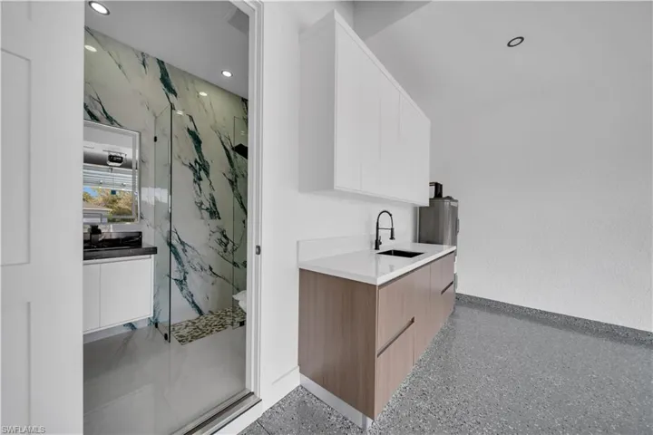 Bathroom with vanity, dark speckled floor, a marble finish shower, and recessed lighting
