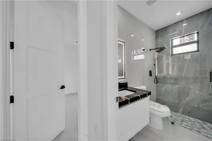 Full bathroom featuring vanity, a marble finish shower, and recessed lighting