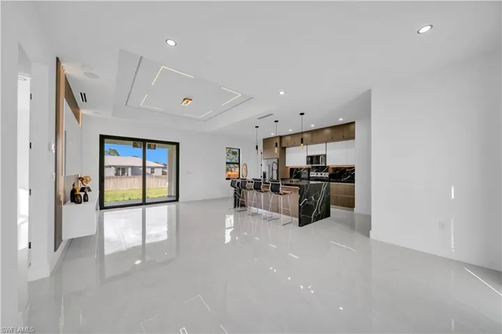 Kitchen with a spacious island, modern cabinets, open floor plan, decorative light fixtures, and a kitchen bar