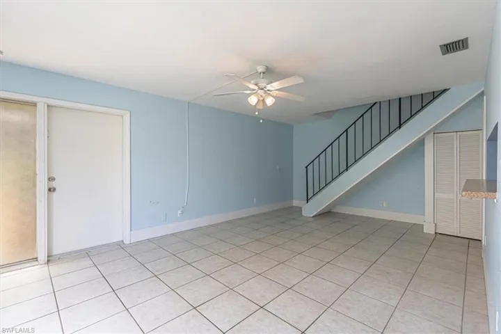 downstairs living room area featuring tile floor and stairs leading up to bedrooms and bathroom on second floor