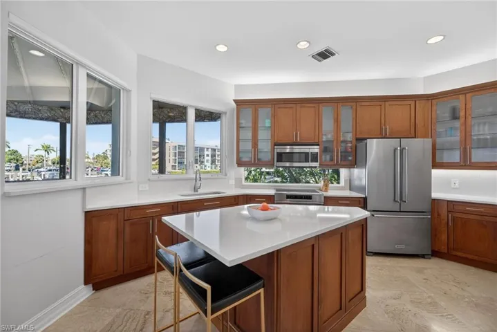 Kitchen featuring wood finish cabinetry, stainless steel appliances, a kitchen bar, a kitchen island, and recessed lighting