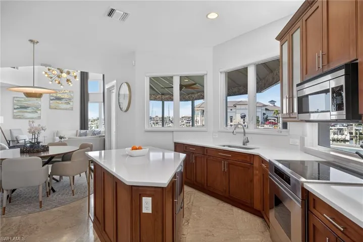 Kitchen featuring stainless steel appliances, wood finish cabinets, pendant lighting, a kitchen island, and open floor plan