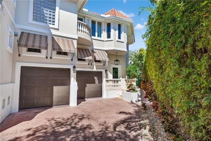 View of front of home featuring stucco siding, a garage, a balcony, and driveway