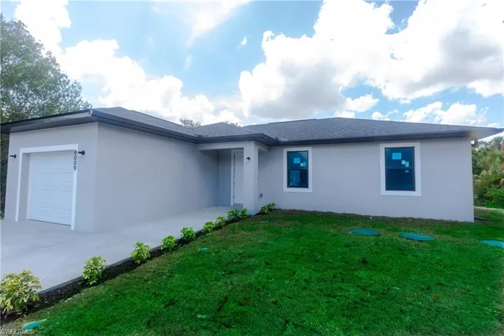 Single story home featuring a garage, stucco siding, concrete driveway, and a front lawn