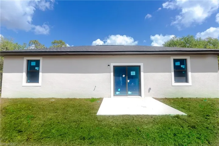Rear view of property with a lawn, stucco siding, and a patio area