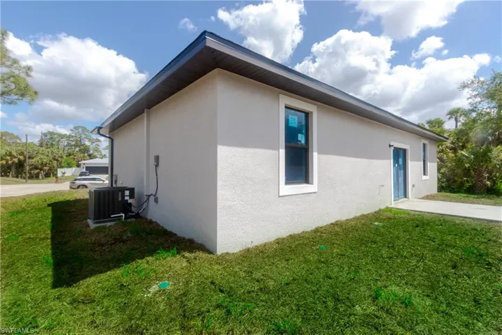 View of home's exterior featuring a lawn, central AC unit, and stucco siding