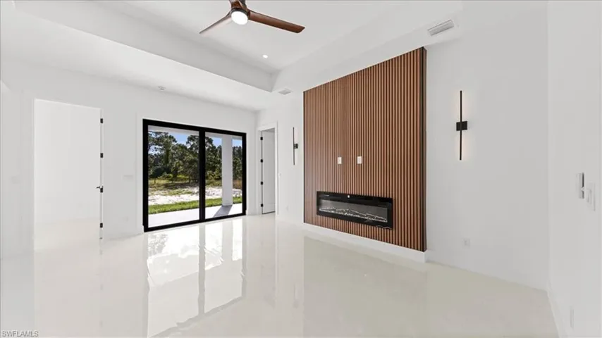 Unfurnished living room featuring a glass covered fireplace, ceiling fan, tile patterned flooring, and recessed lighting