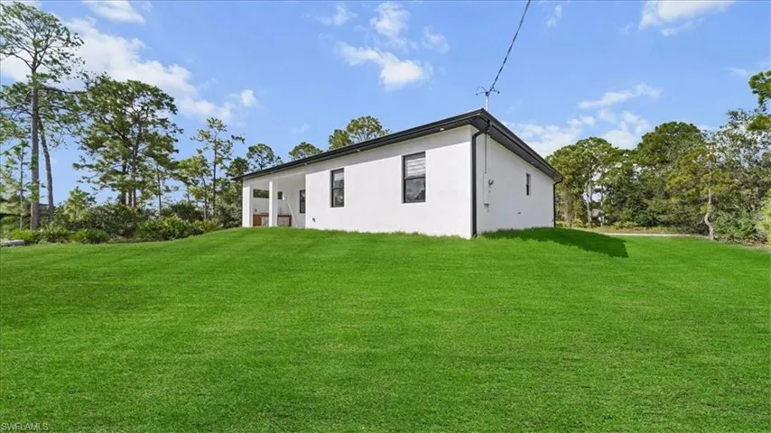 Rear view of house with a lawn and stucco siding