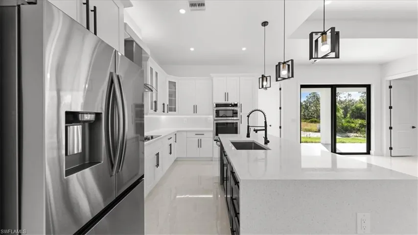 Kitchen with stainless steel appliances, white cabinetry, light stone countertops, pendant lighting, and recessed lighting