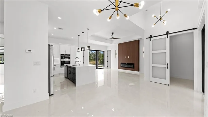 Kitchen featuring a barn door, a chandelier, white cabinetry, a ceiling fan, and open floor plan