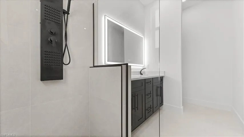 Bathroom with double vanity, light tile patterned floors, and tiled shower