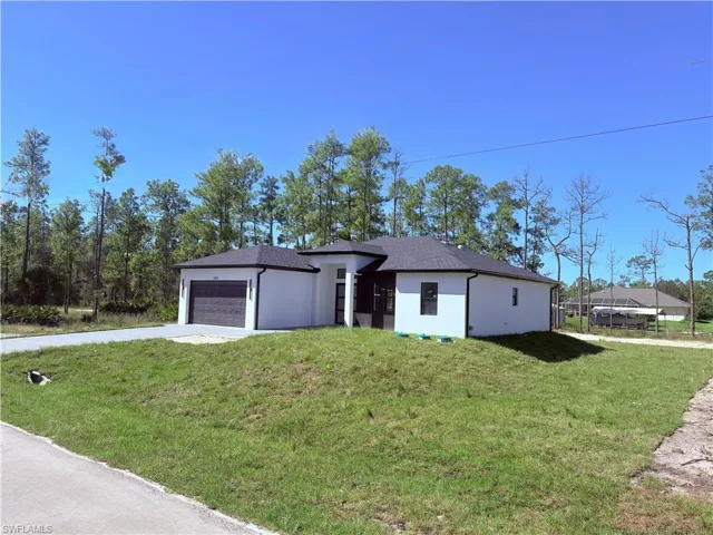 View of front of house featuring a front lawn, stucco siding, concrete driveway, and a garage